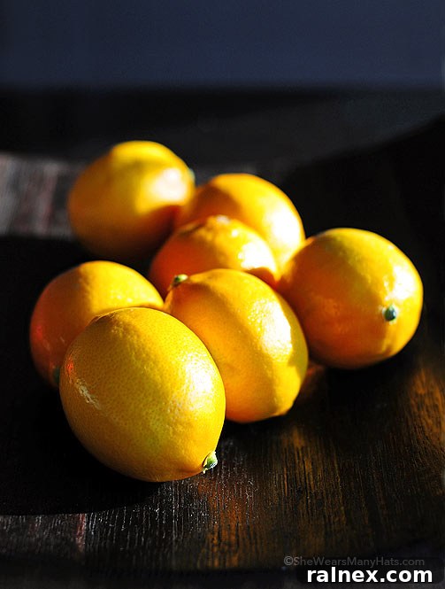 A cluster of fresh, vibrant Meyer lemons on a rustic wooden surface, ready for zesting
