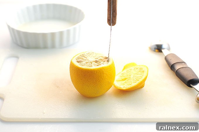 Crafting Irresistible Lemon Cups 8 Step 7: Using a melon baller to gently scoop out the lemon pulp from the hollowed rind, maintaining its shape.
