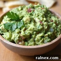 Guacamole Recipe served in a beautiful white bowl with fresh ingredients scattered around