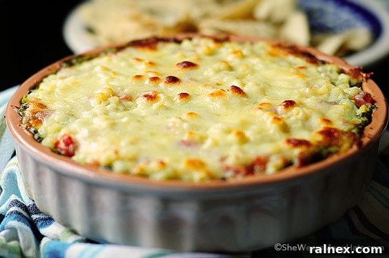 Close-up shot of the Warm Layered Black Bean Dip showing melted cheese, corn, and tomato topping, irresistible and warm.
